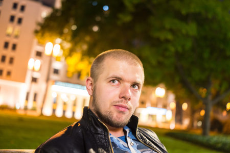 Handsome young hipster outside in the night cityの写真素材