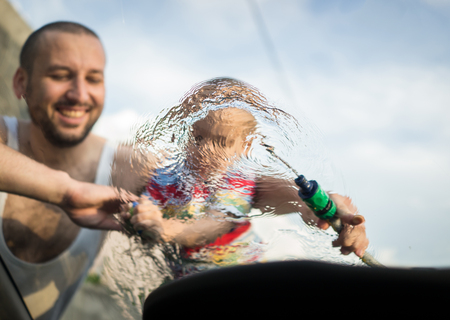 Young father and little boys washing car in summer dayの写真素材