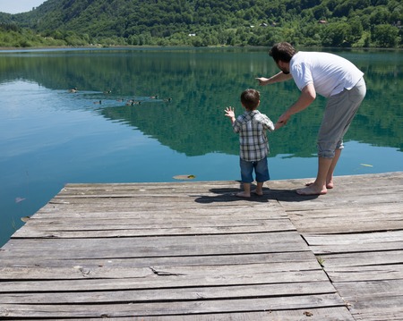 Dad and son playing on the mountain lakeの写真素材