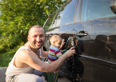 Young father and little boys washing car in summer dayの写真素材
