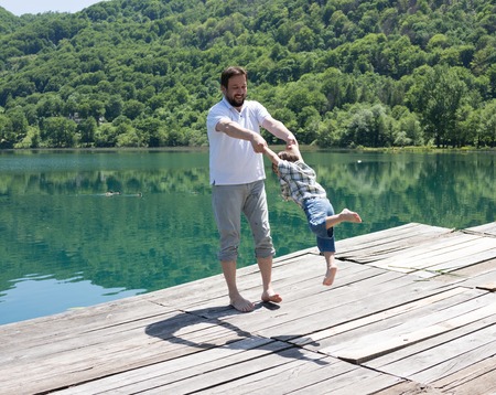 Dad and son playing on the mountain lakeの写真素材