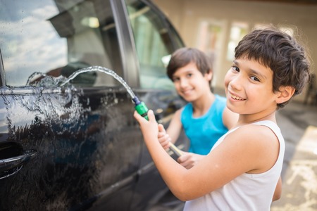 Young father and little boys washing car in summer dayの写真素材