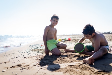 Playful kids on summer beach sand vacation having fun and happy timeの写真素材