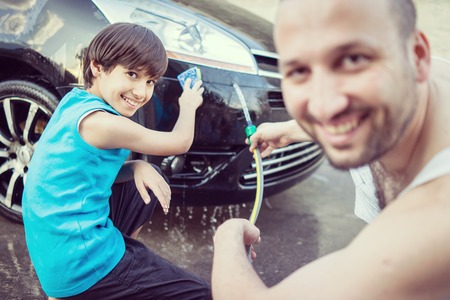 Young father and little boys washing car in summer dayの写真素材