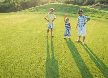 Kids on beautiful green meadow with long shadowsの写真素材