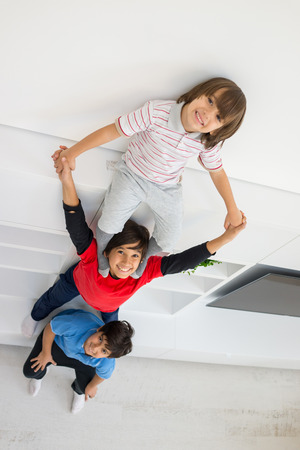 Cheerful funny children having fun and posing line up piggyback in new modern home top viewの写真素材