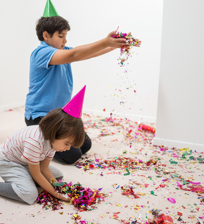 Happy kids celebrating party with blowing confettiの写真素材