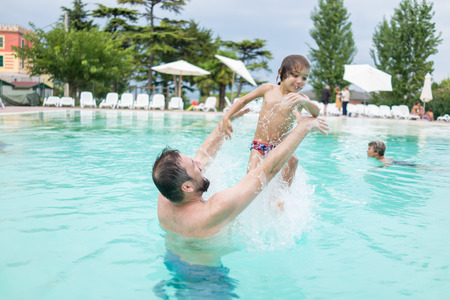 Young boy kid child splashing in swimming pool having fun leisure activityの写真素材