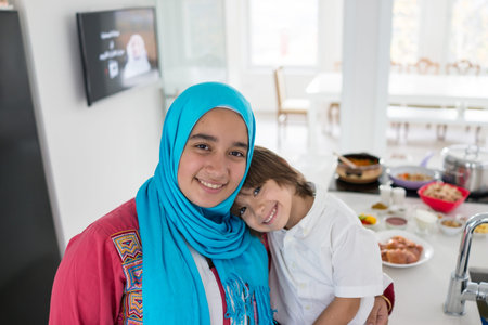 Muslim traditional woman with little son in modern white kitchen