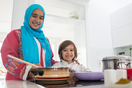 Muslim traditional woman with little son in modern white kitchenの写真素材