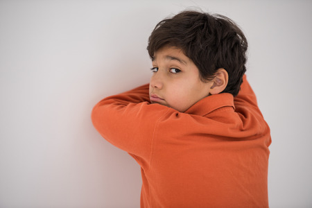 Kid hiding face on the wallの写真素材