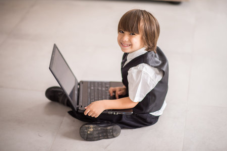 Little cute boy with laptop at home
