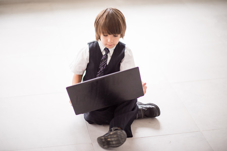 Cute kid with laptop on ground at homeの写真素材