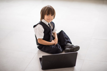 Cute kid with laptop on ground at homeの写真素材