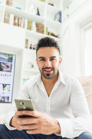 Young good looking man at home using a phoneの写真素材