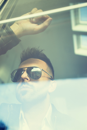 Double exposure confident attractive young man looking through the window glassの写真素材