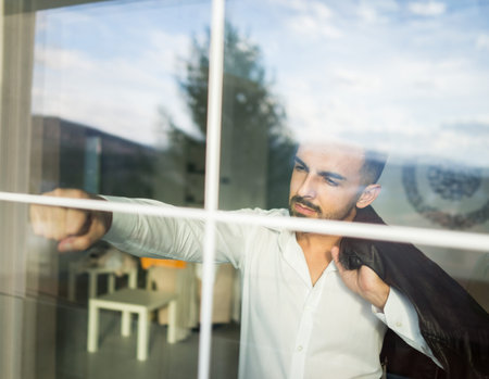 Double exposure confident attractive young man looking through the window glassの写真素材