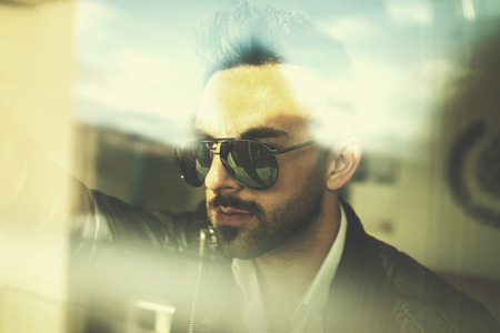 Double exposure confident attractive young man looking through the window glassの写真素材
