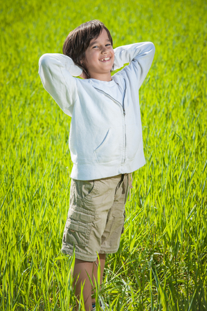 Happy child on beautiful green yellow grass fieldの写真素材