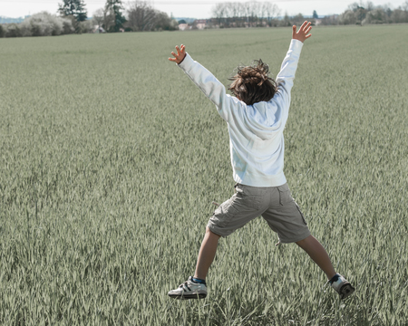 Happy child on beautiful green yellow grass fieldの写真素材