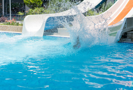 Children enjoying in pool water slide at poolの写真素材