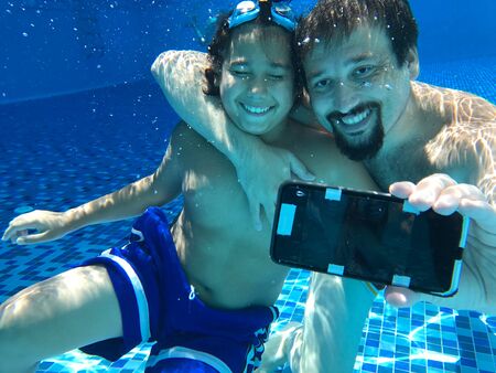 Father and son taking selfie underwaterの写真素材