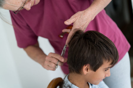 Senior woman cutting boy's hair