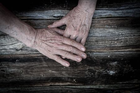 Senior hands on old wooden backgroundの写真素材