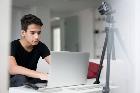 Young boy talking online using laptop and camera equipmentの写真素材