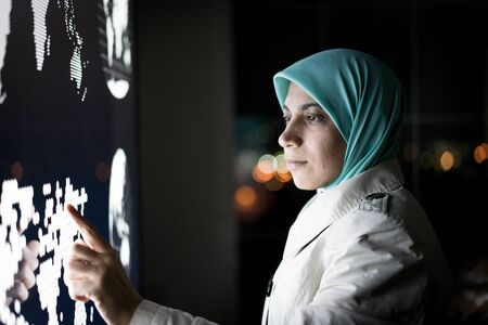 Muslim woman working on smart infographic screenの写真素材