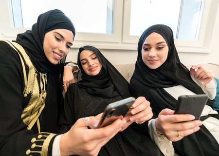 Muslim girls sitting together with smart phones