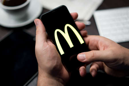 New York, New York / USA - 11 11 2019: Logo of Mcdonalds on the iPhone X in hands in officeのeditorial素材