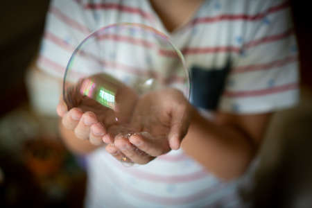 Little creative kid having fun with soap bubble in lockdownの写真素材