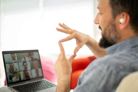 Mid adult man having online conference working at homeの写真素材