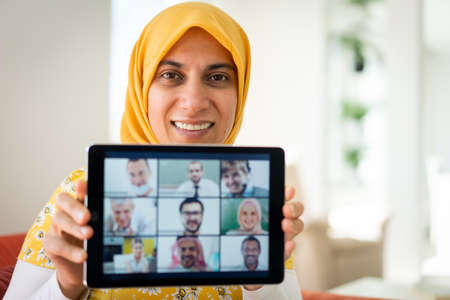 Muslim womah holding tablet with zoom conference screenの写真素材
