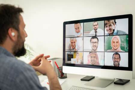 Mid adult man having online conference working at homeの写真素材