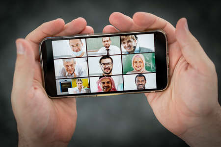 Online business conference screen in hands new normalの写真素材