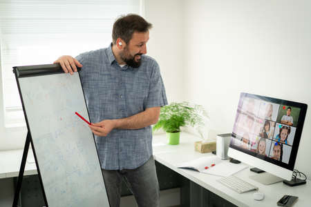 Male teacher having online conference with school children working at homeの写真素材