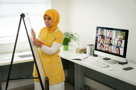 Arabic female teacher working with children online school during pandemicの写真素材