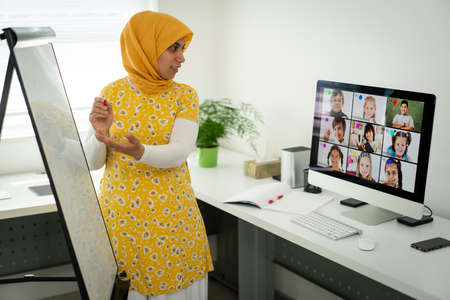 Arabic female teacher working with children online school during pandemicの写真素材
