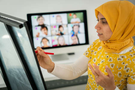 Arabic female teacher working with children online school during pandemicの写真素材