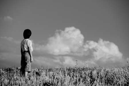 Kid standing on meadow alone , white blackの写真素材