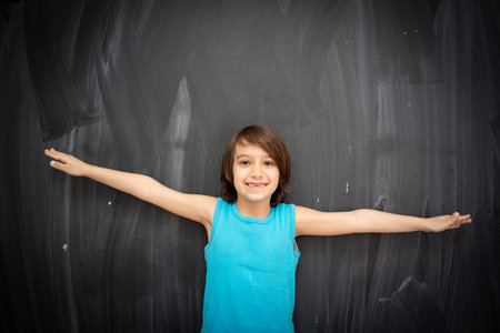 Little cute boy in front of classroom chalkboardの写真素材