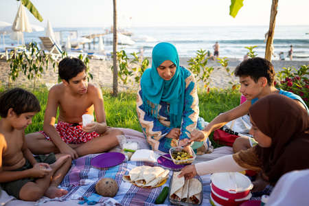 Happy family enjoying picnic on beach near seaの写真素材