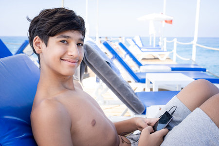 Teenage boy sitting on pier chair and enjoyingの写真素材