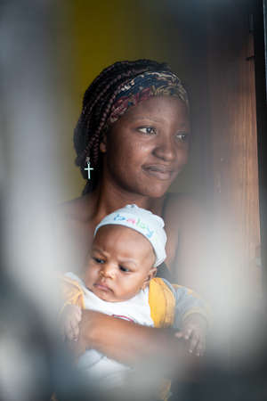 African American young mother holding her baby indoorsの写真素材