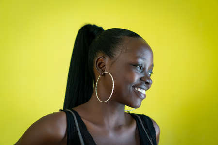 Beautiful dark skin young woman portrait on yellowの写真素材