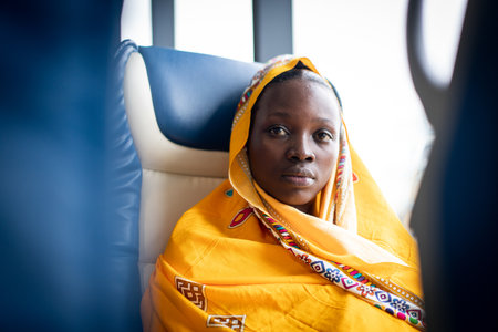 Beautiful black young woman traveling alone near windowの写真素材