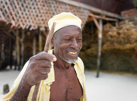 Aged African shepard walking on the beach holding stickの写真素材