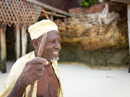 Aged African shepard walking on the beach holding stickの写真素材